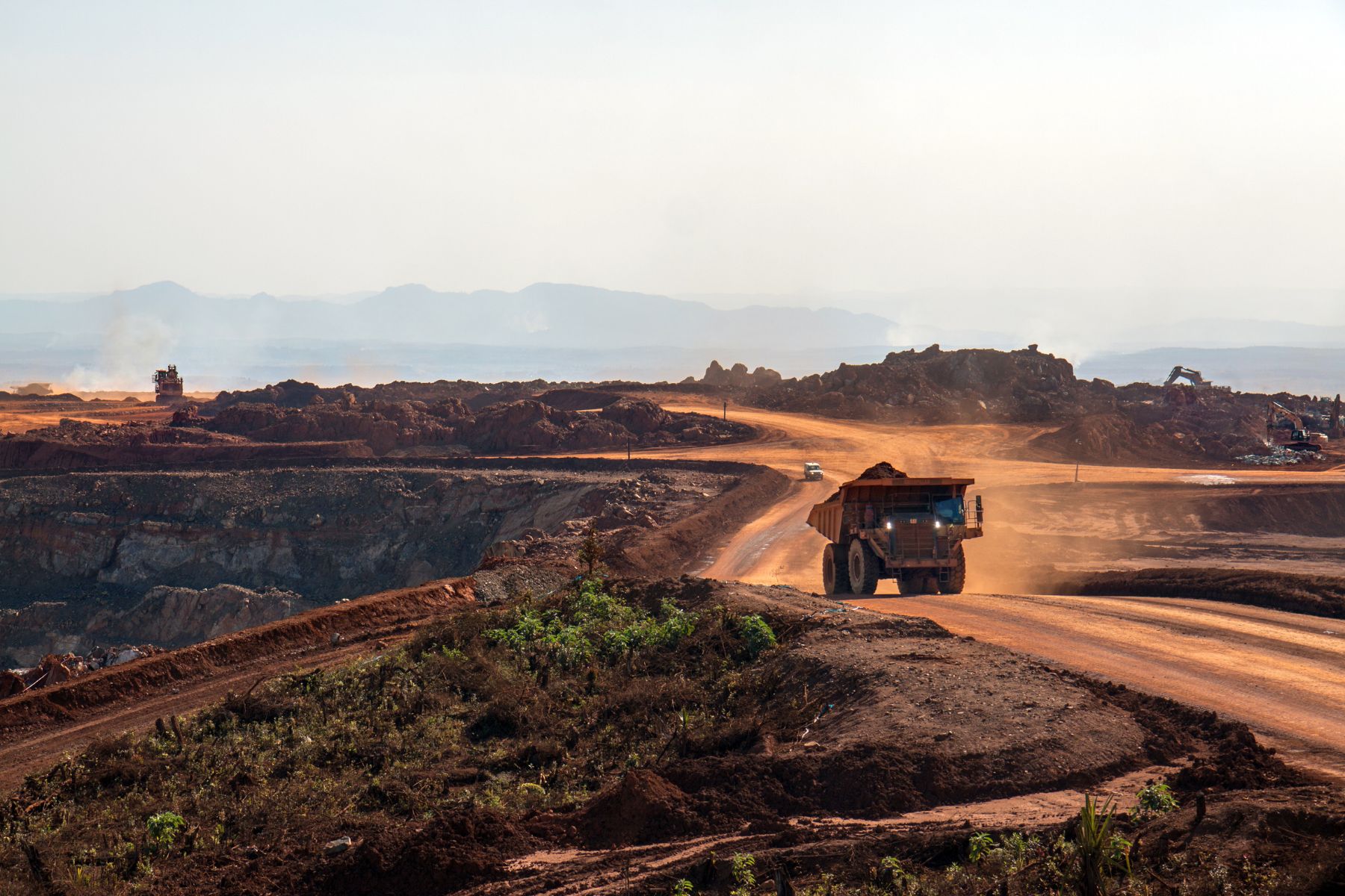 Un paysage de mine à ciel ouvert avec au premier plan un camion qui roule.